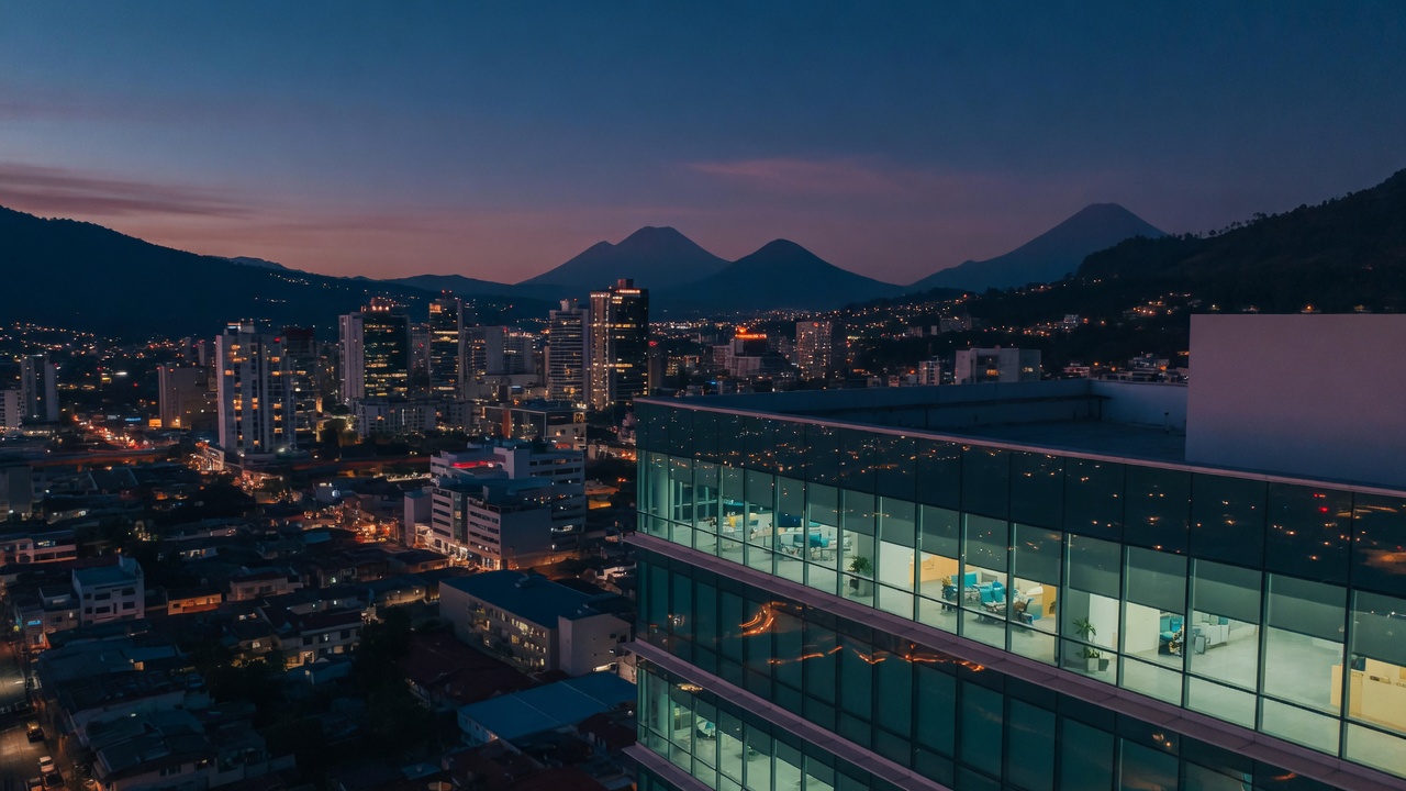Ciudad de Guatemala al anochecer, con montañas al fondo.